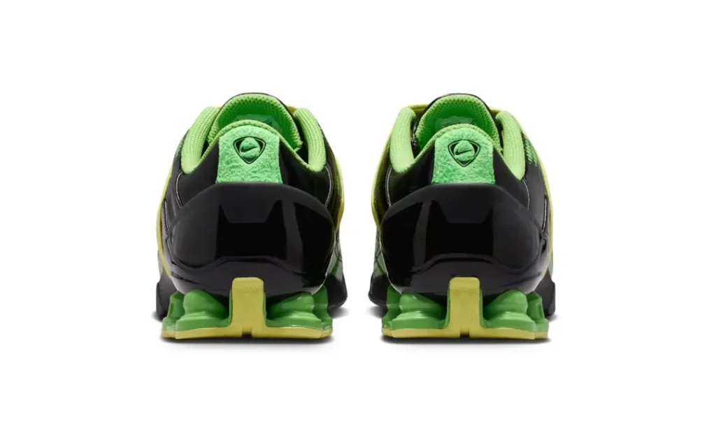 Rear view of the green shoe showing glossy molded heel supports, embroidered tongue branding, and bright green Shox column
