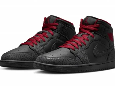 Black and red Air Jordan 1 Mid shoe displayed as a pair from a front three-quarter angle, featuring smooth black leather, tonal elephant-print overlays, crimson laces, and matching Wings branding on a clean white background