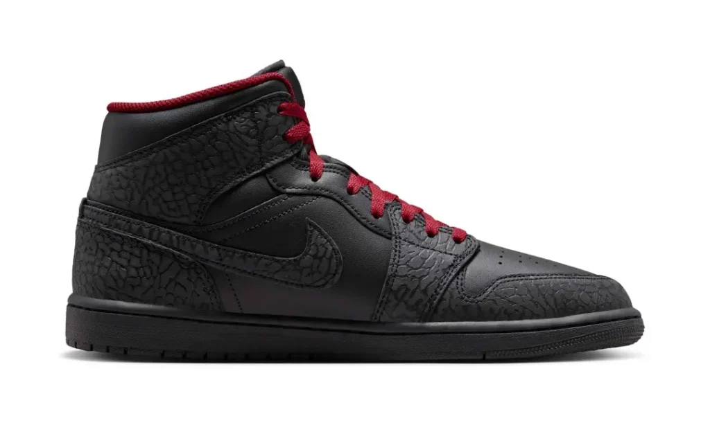 Medial side profile of the Air Jordan 1 Mid highlighting black leather construction, elephant-print overlays wrapping the toe and heel, tonal Swoosh, crimson collar lining, and black midsole