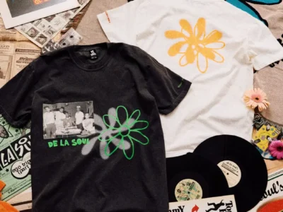 De La Soul x WIND AND SEA collaboration apparel displayed alongside vinyl records, magazines, flowers, and a turntable, featuring graphic T-shirts inspired by the legendary hip-hop group's iconic daisy imagery