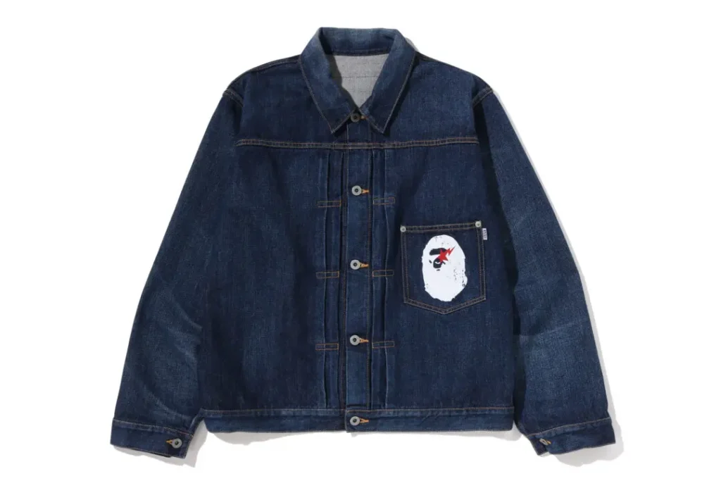 Dark indigo A BATHING APE denim trucker jacket with oversized fit, contrast stitching, and ape-head pocket graphic