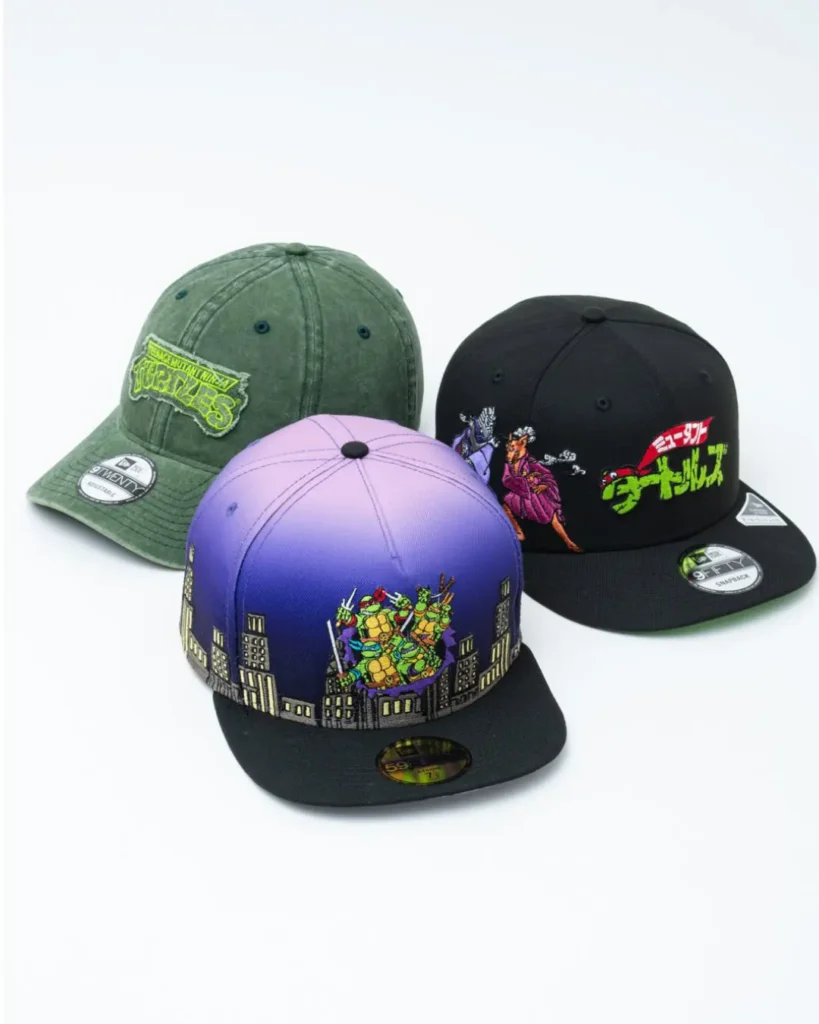Three Teenage Mutant Ninja Turtles x New Era caps displayed against a clean white background. The collection includes a washed olive-green 9TWENTY cap with a distressed TMNT logo patch, a black 9FIFTY snapback featuring Japanese-inspired Turtle artwork and bold neon-green lettering, and a purple-to-blue gradient fitted cap embroidered with the four turtles emerging above a stylized city skyline
