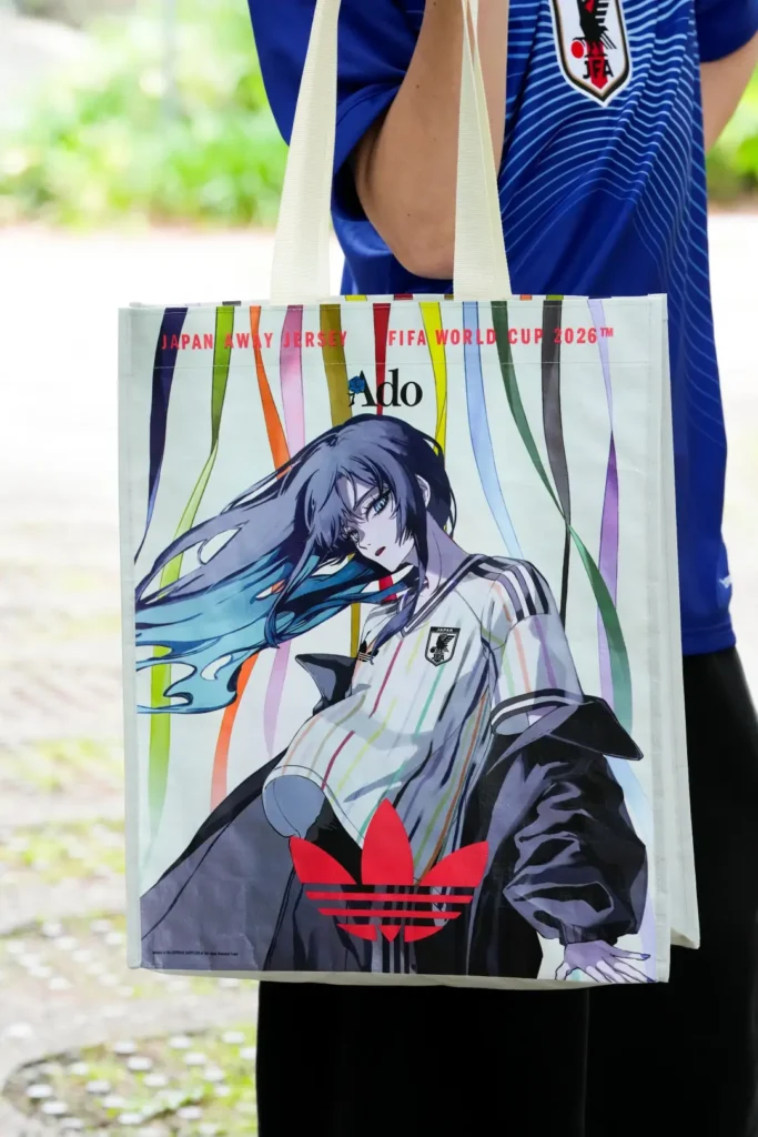 Ado x adidas Japan away jersey tote bag featuring colorful ribbon graphics, anime artwork, and FIFA World Cup 2026 brand