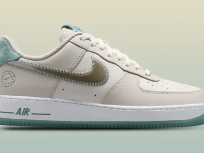 Nike Air Force 1 Low in a clean sail leather construction featuring a reflective metallic silver Swoosh outlined with aqua stitching. Soft terry-cloth heel tabs in pastel blue add texture, while translucent icy-blue outsoles provide a fresh contrast. Subtle Philly-inspired branding appears near the heel, with matching aqua accents on the midsole “AIR” logo