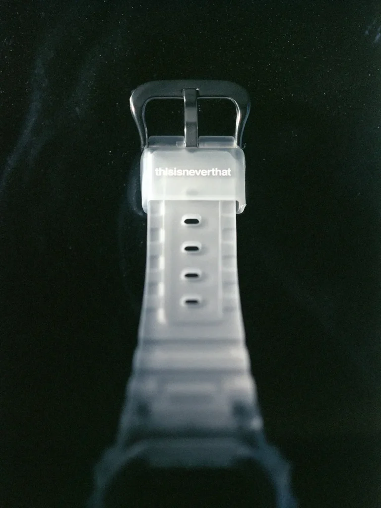 Close-up of the translucent strap and buckle viewed from above. The frosted resin band features subtle thisisneverthat branding near the keeper, while the dark background draws attention to the minimalist design and semi-transparent material