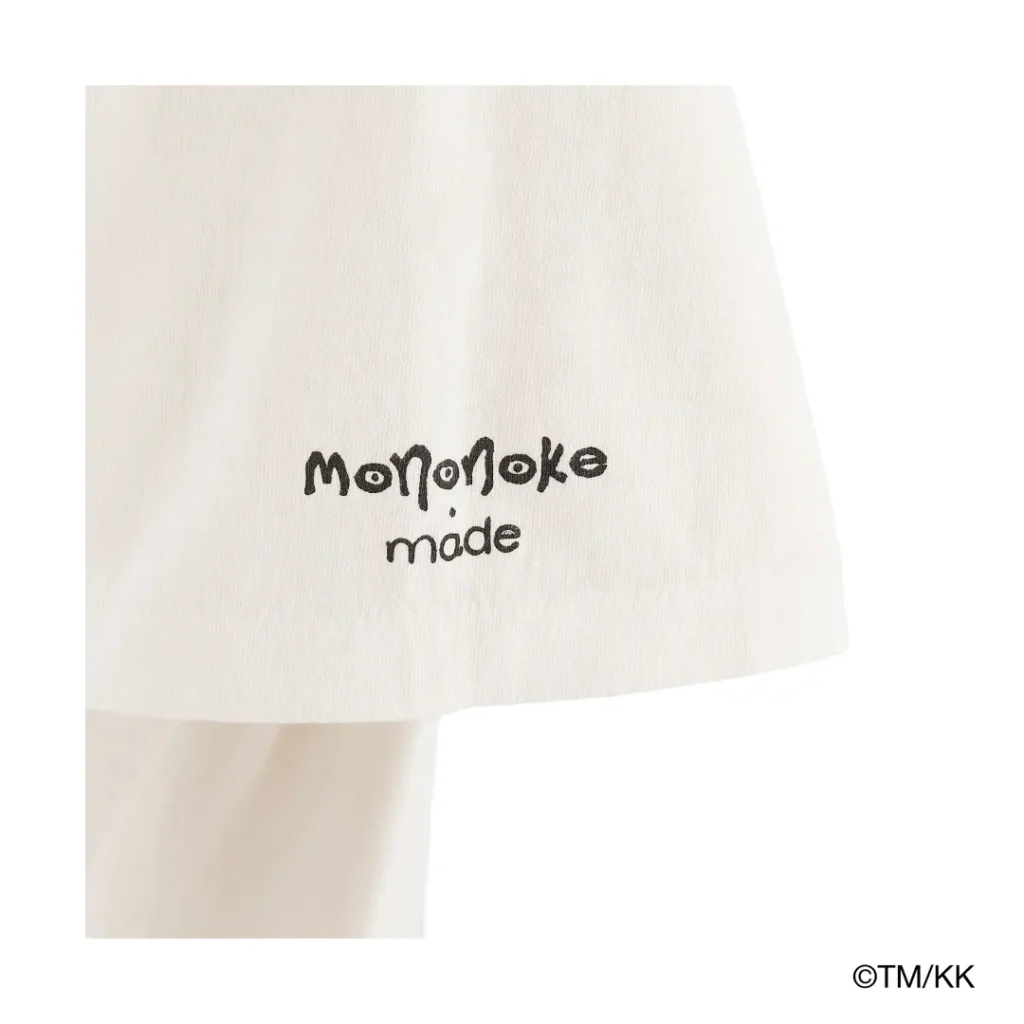 Detailed view of embroidered “Mononoke made” branding near the hem of a white T-shirt. The minimalist stitching adds a subtle finishing touch