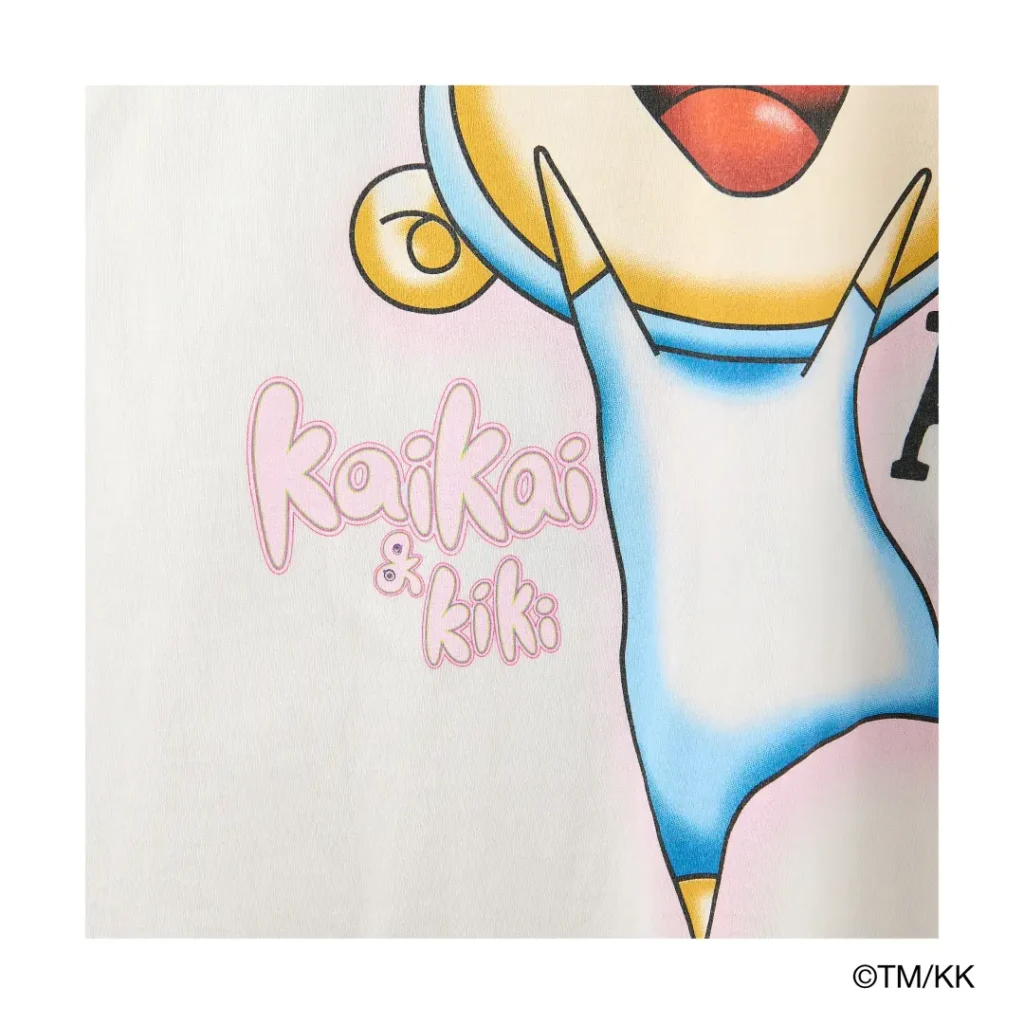 Detailed close-up of a colorful character graphic with pastel tones, cartoon features, and “Kaikai & Kiki” branding. The print showcases vibrant shading and playful Murakami-inspired artwork