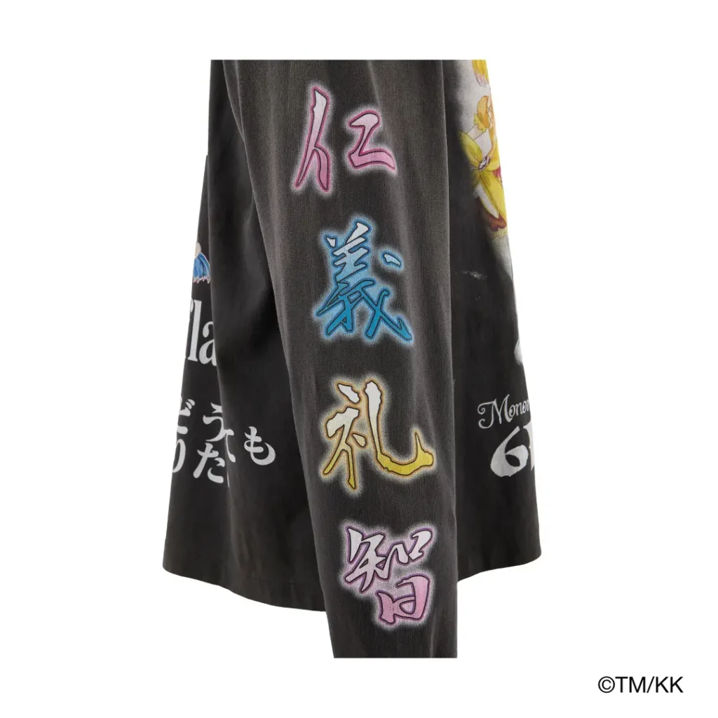 Close-up of a black garment sleeve decorated with multicolored Japanese characters outlined in neon-style hues. The graphic placement adds visual depth and anime-inspired flair to the piece