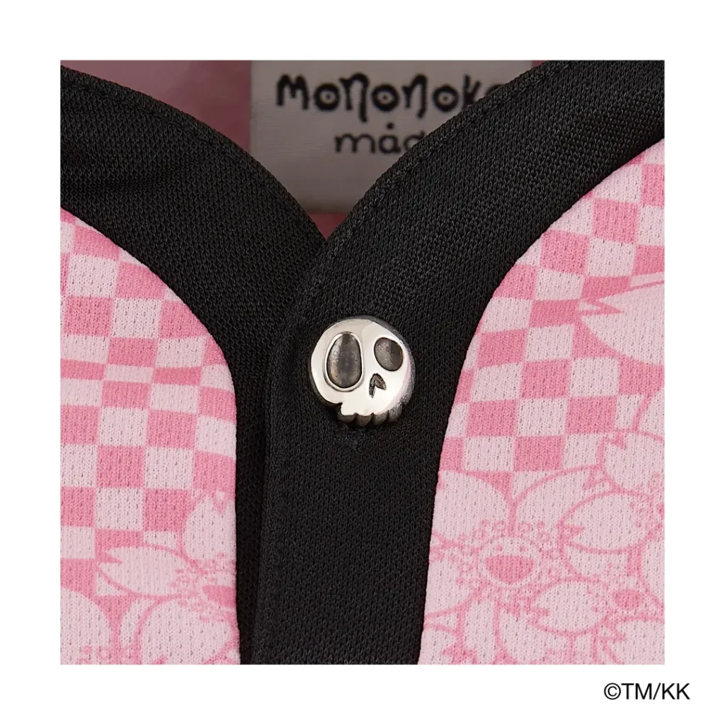 Detailed view of a black-and-pink collar featuring a metallic skull-shaped button fastening. The contrast between playful floral patterns and edgy hardware creates a distinctive finishing touch