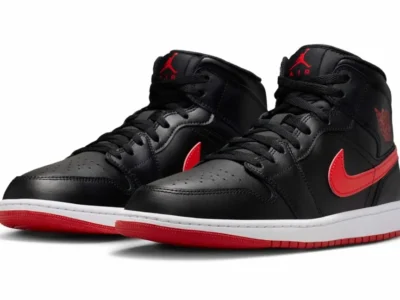 Pair of Air Jordan 1 Mid sneakers in black leather with bold red Swooshes, matching red outsoles, and white midsoles. The classic basketball silhouette is presented in a clean studio setting, highlighting its timeless tincture-blocking
