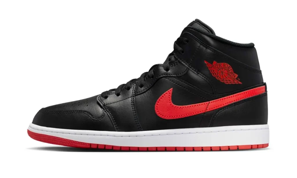 Lateral side profile of the Air Jordan 1 Mid showcasing smooth black leather construction, a vivid red Swoosh, and embossed red Air Jordan Wings branding near the collar. The white midsole adds sharp contrast to the design