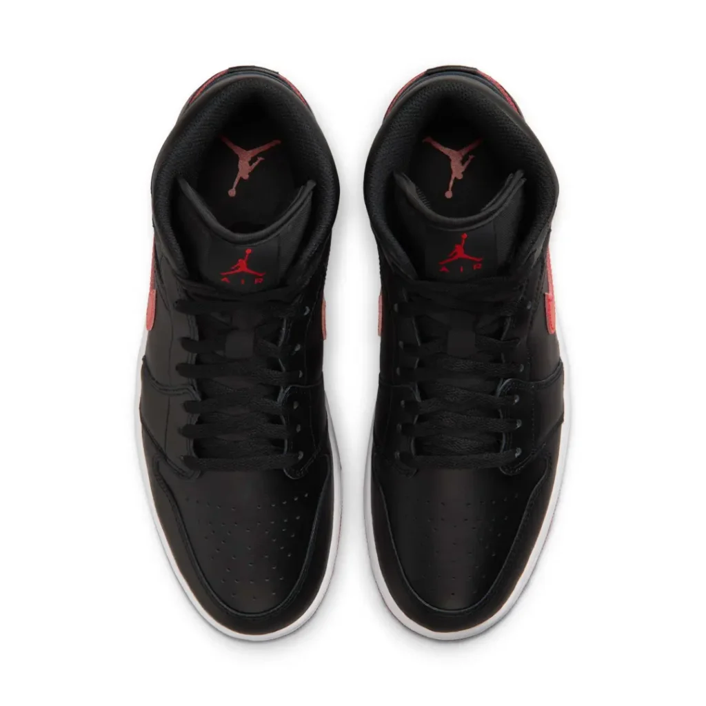 Top-down view of the Air Jordan 1 Mid displaying black laces, perforated toe boxes, padded collars, and red Jumpman logos on the tongues. The symmetrical composition highlights the shoe classic construction