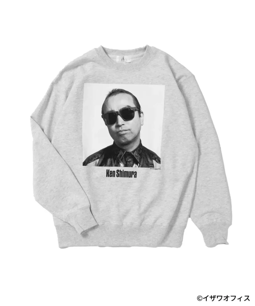 Heather gray crewneck sweatshirt with a centered black-and-white portrait of Ken Shimura wearing sunglasses. The oversized front graphic is paired with his printed name below, while the soft fleece construction and ribbed trim give the classic sweatshirt a clean, casual appearance