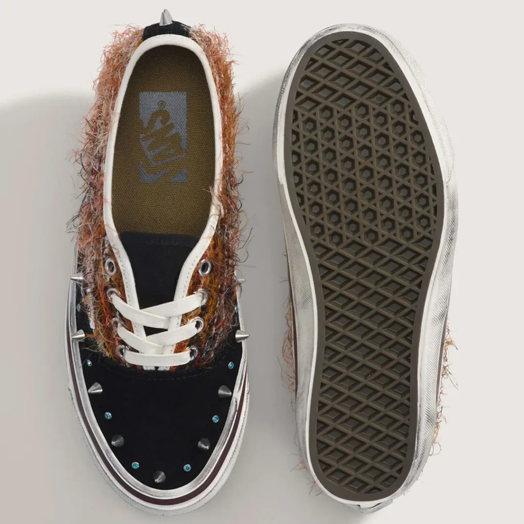 Top-and-bottom product view of the black pair. The image reveals the studded toe box, white lace setup, textured woven materials, Vans-branded footbed, and the classic waffle outsole pattern