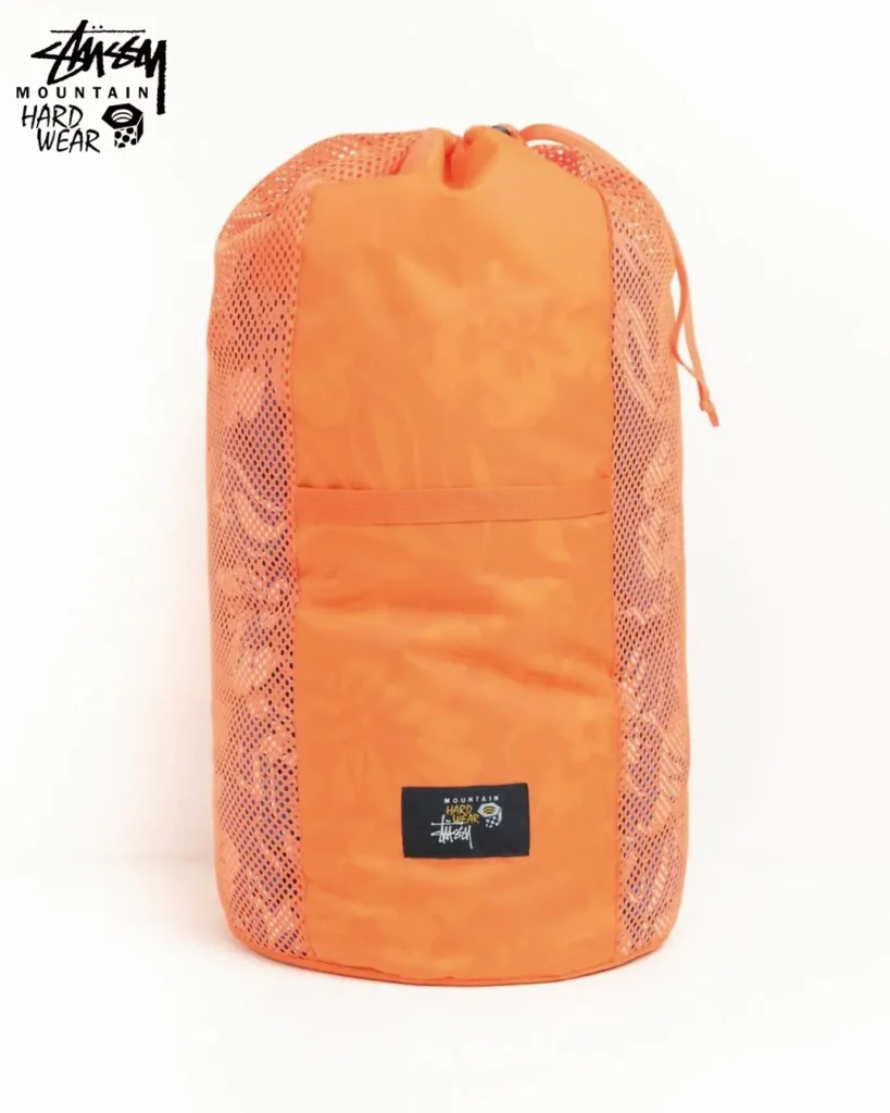 Orange mesh storage bag designed for camping gear organization, featuring collaborative Stüssy x Mountain Hardwear branding and lightweight construction