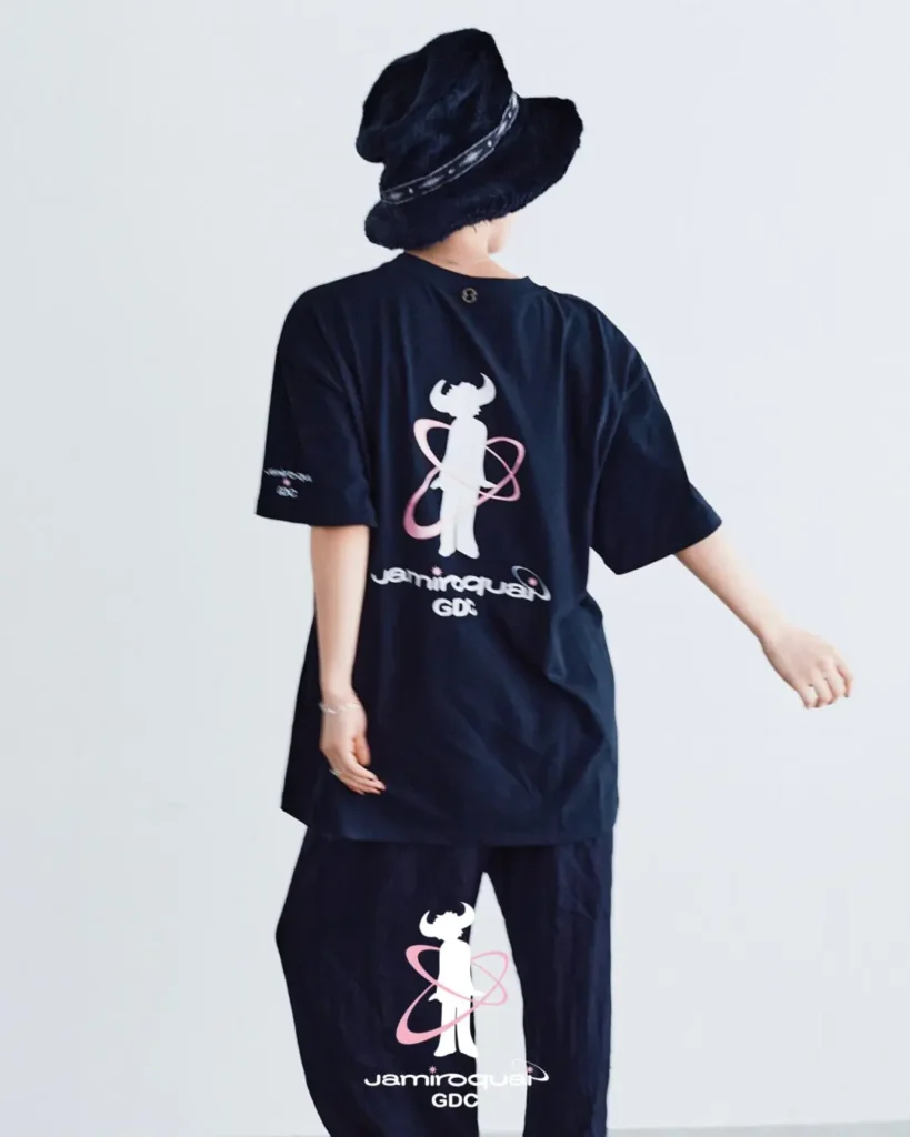 Rear-facing campaign shot highlighting the oversized back print of the Jamiroquai x GDC T-shirt. The graphic features the recognizable buffalo-man figure surrounded by pink orbital lines and collision wordmark