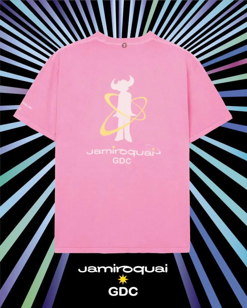 The oversized tee features a large graphic on the back combining Jamiroquai’s iconic buffalo-man silhouette in white with orbit-like yellow rings, accompanied by co-branded Jamiroquai and GDC logos beneath. The soft pink cotton body contrasts with the cosmic-inspired artwork, blending late-1990s electronic music aesthetics with contemporary Japanese streetwear design