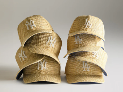 Stack of woven raffia-style MLB caps featuring New York Yankees and Los Angeles Dodgers logos in natural straw tones against a neutral studio backdrop