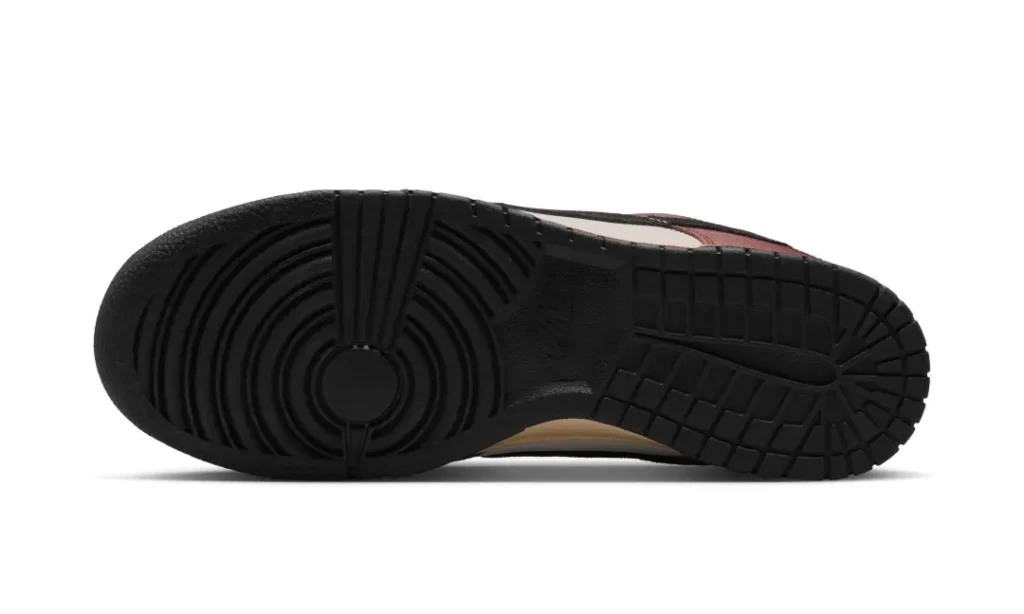 Bottom view of the Nike Dunk Low displaying a solid black rubber outsole with classic circular traction pattern at the forefoot and pivot point