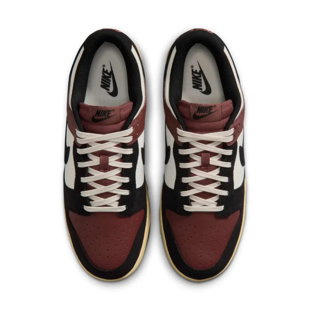 Top-down view of the burgundy Nike Dunk Low showing cream laces, burgundy perforated toe boxes, matching tongue, black collar lining, and Nike-branded insole