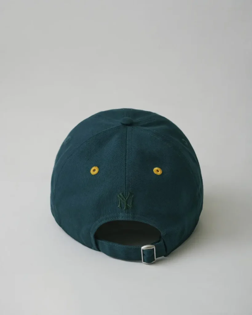 Rear view of the dark teal Yankees cap showing yellow eyelet detailing, tonal back logo embroidery, and an adjustable buckle strap