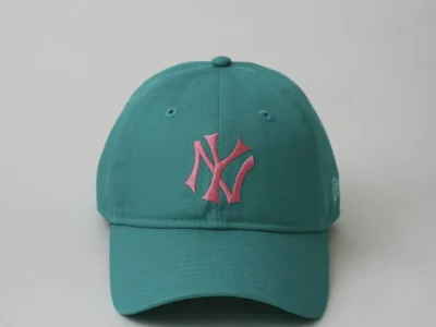 Front view of a turquoise New York Yankees cap showcasing a pink embroidered NY logo, pastel-inspired color palette, and curved brim