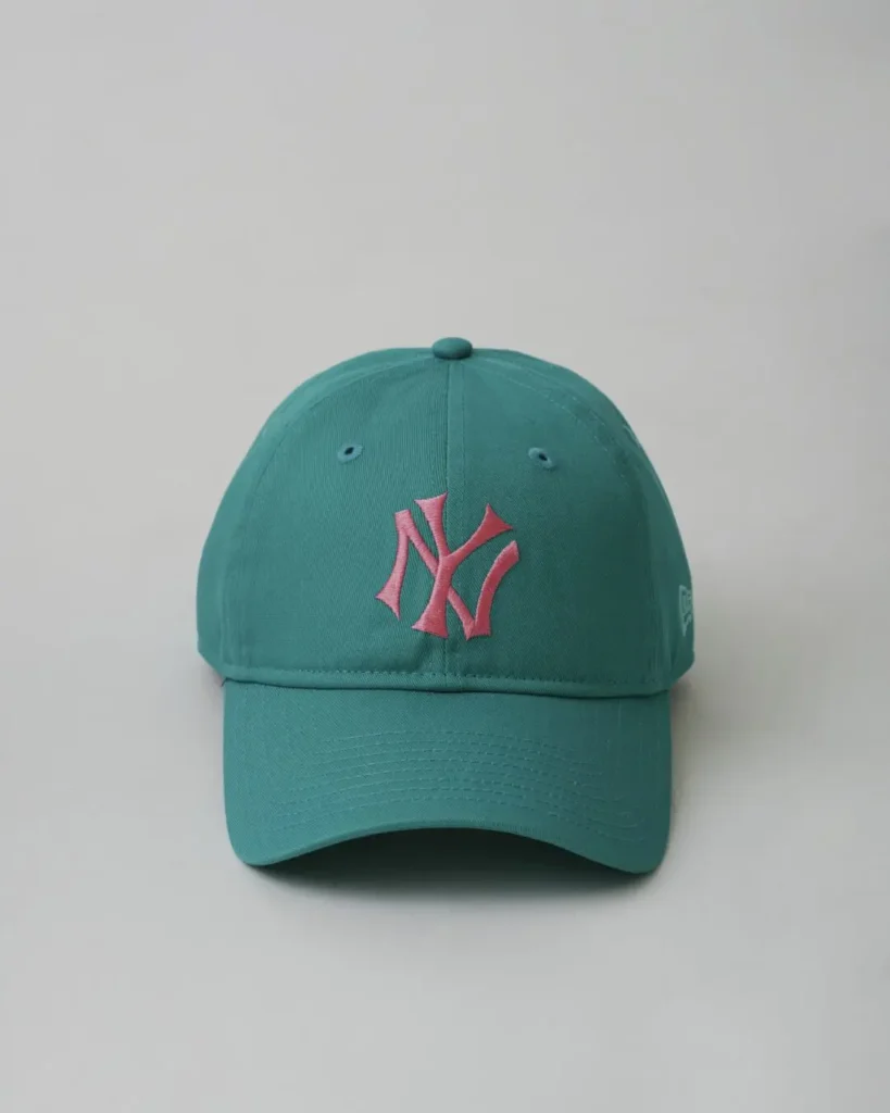 Front view of a turquoise New York Yankees cap showcasing a pink embroidered NY logo, pastel-inspired color palette, and curved brim