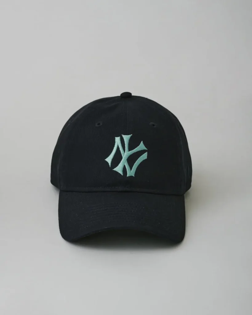 Front view of a black New York Yankees adjustable baseball cap featuring a mint-green embroidered NY logo on the crown and a curved brim