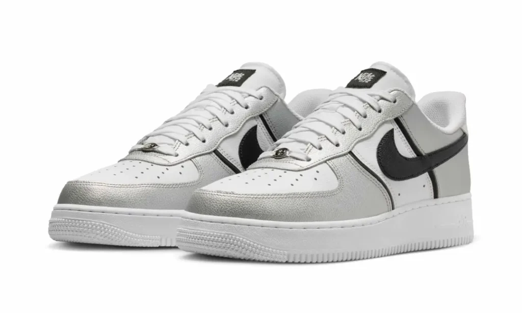 Nike Air Force 1 Low sneakers in metallic silver, white, and black, shown in an angled pair view highlighting reflective silver overlays, black leather Swooshes, white leather panels, and crisp white mid