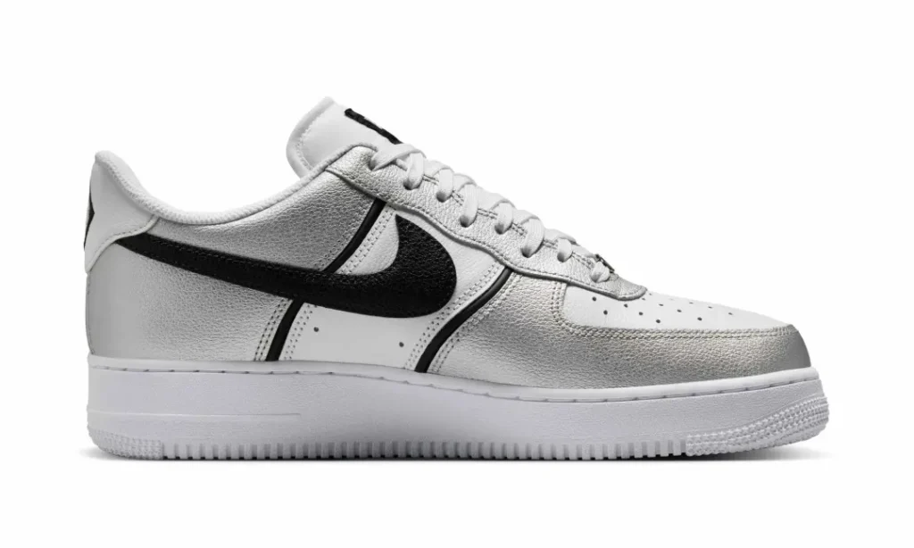 Lateral side view of the Nike Air Force 1 Low emphasizing the contrast between the metallic silver leather overlays, black Swoosh, and clean white base