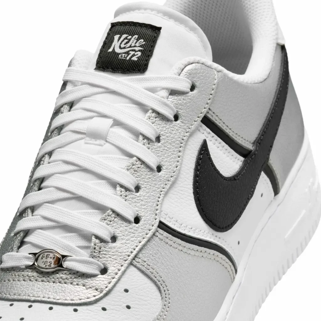 Close-up of the forefoot and eyestay area featuring textured metallic silver leather, white tumbled leather panels, black leather Swoosh, and a chrome AF1 lace dubrae