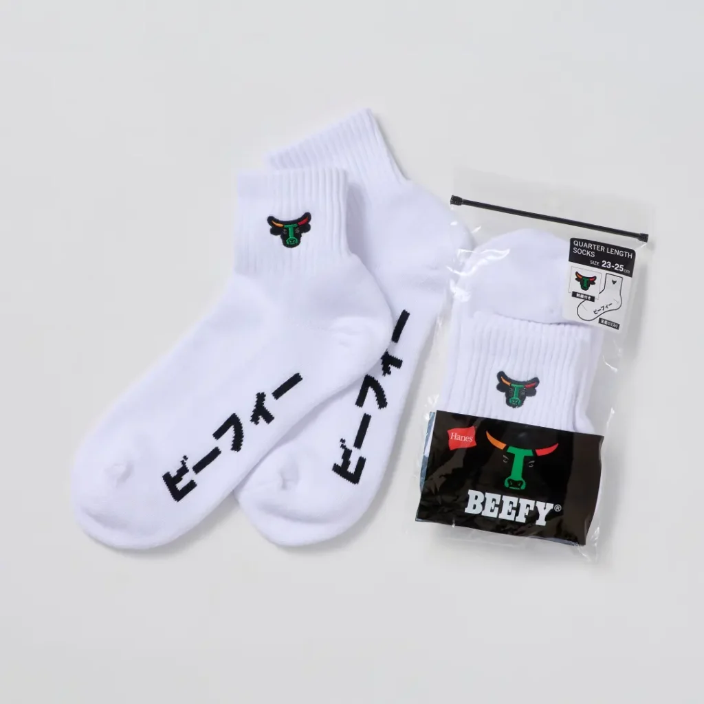 White Hanes BEEFY quarter-length socks displayed alongside their retail packaging. The socks feature embroidered bull-head logos at the cuffs and bold Japanese lettering along the footbed