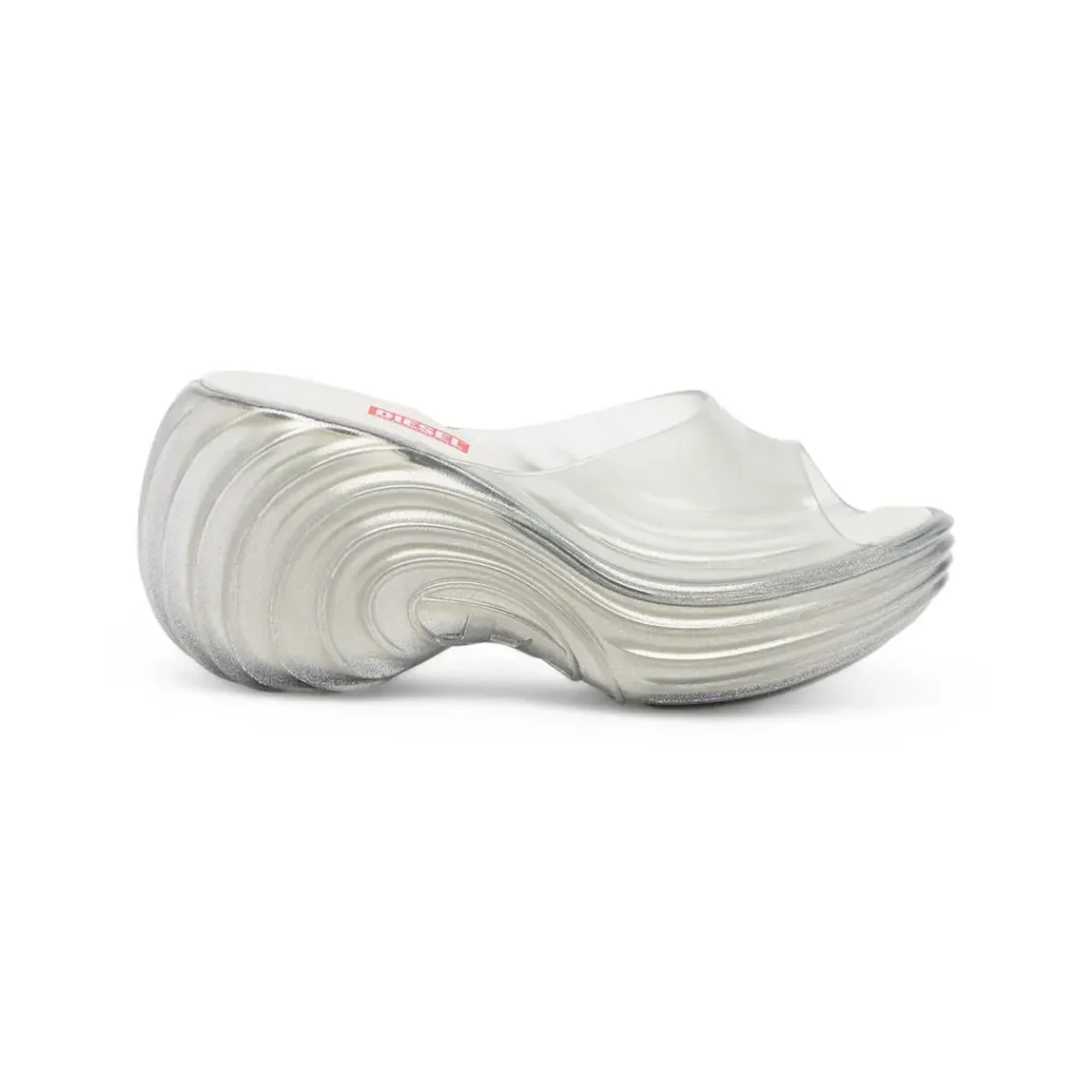 Product image of a metallic silver Melissa × Diesel platform slide with translucent upper, showcasing its flowing wave-like sculpted sole and futuristic sil