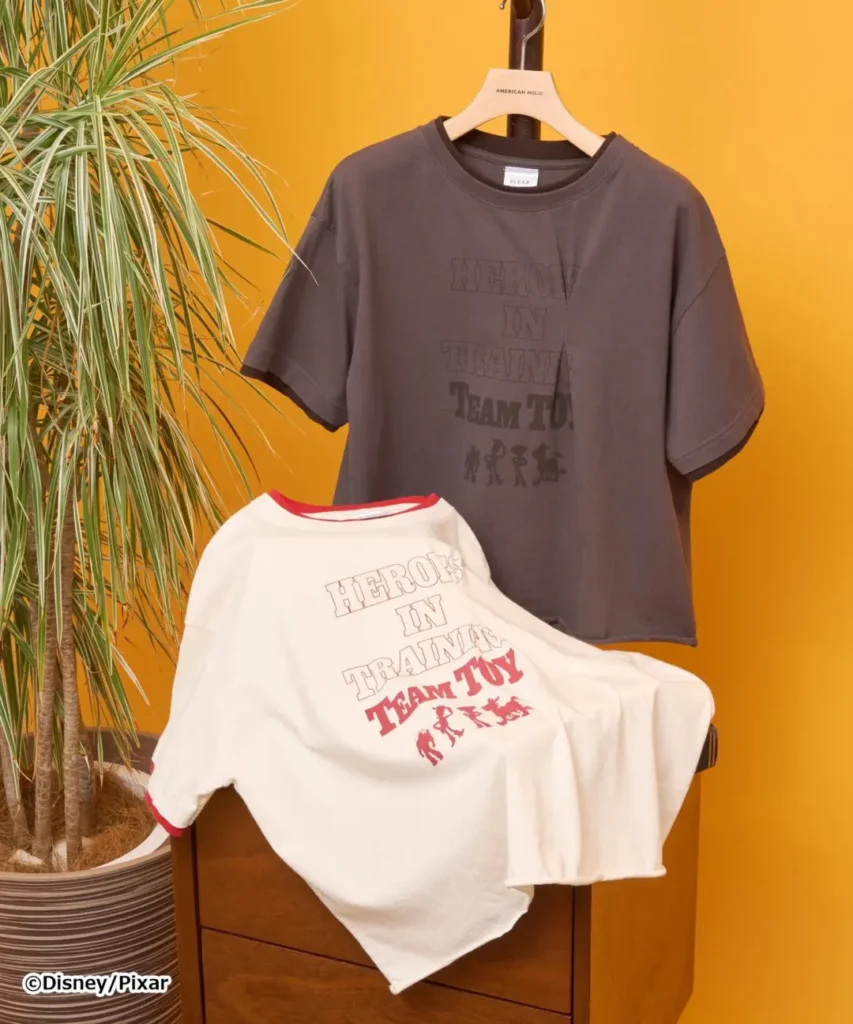 Team Toy graphic ringer T-shirts in cream and charcoal colorways featuring retro athletic-inspired typography and character silhouettes from the Toy Story universe