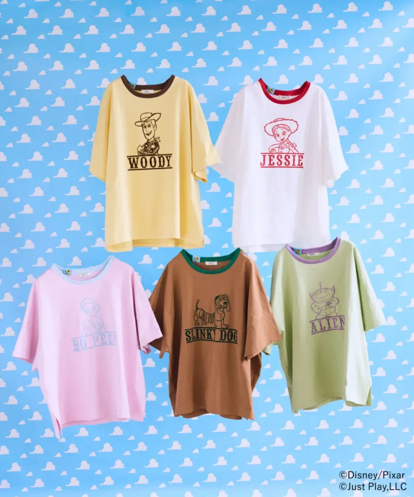 Pastel oversized Toy Story graphic T-shirts featuring Woody, Jessie, Bo Peep, Slinky Dog, and Alien character illustrations arranged against a sky-blue cloud background