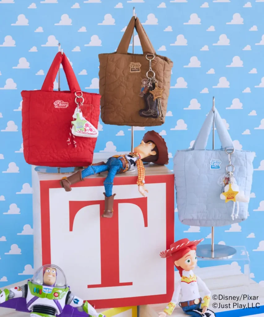 Quilted Toy Story tote bags in Pizza Planet red, Woody brown, and cloud blue colorways displayed alongside Woody, Jessie, and Buzz Lightyear figure