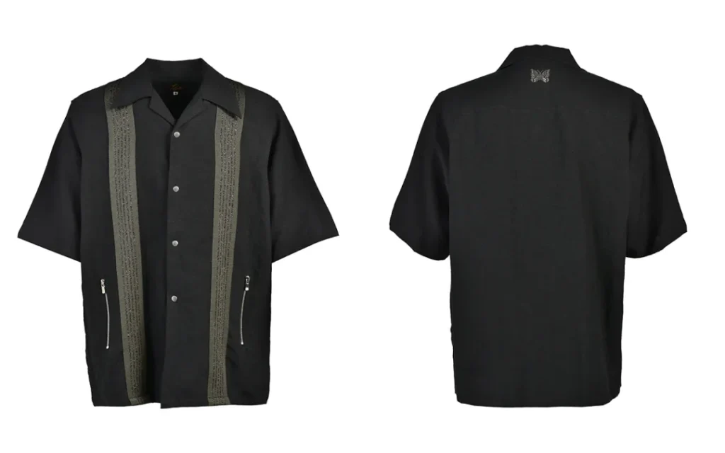 Front and back product views of the NUBIAN × Needles short-sleeve open-collar shirt featuring embroidered vertical panels, silver zipper pockets, and butterfly logo embroidery on the back