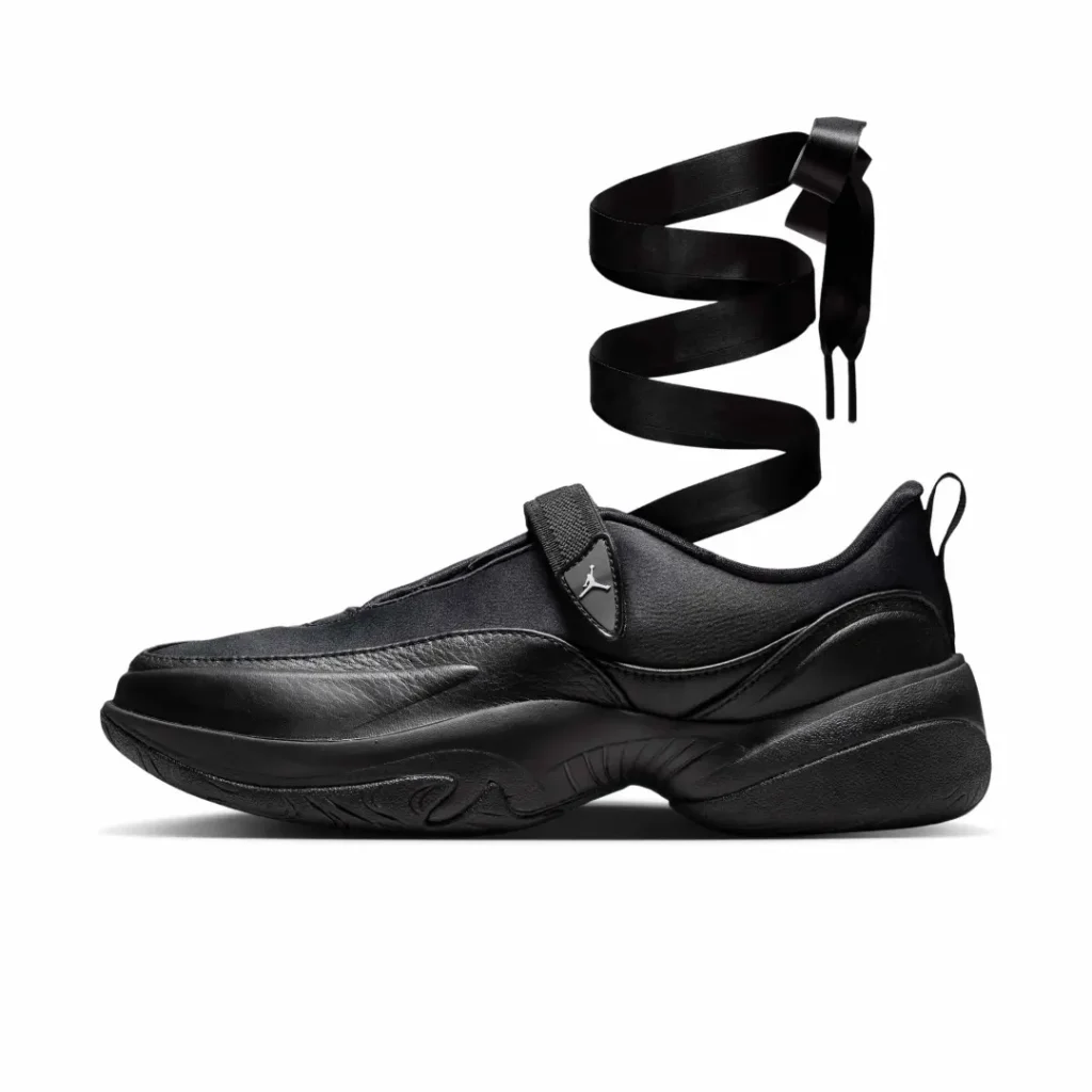 Side profile of an all-black Air Jordan women’s lifestyle shoe with a sculpted chunky sole, elastic midfoot strap, and long satin ribbon lace extending upward
