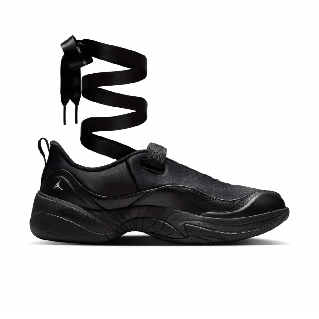 Lateral side view of the monochromatic black Air Jordan silhouette highlighting smooth leather overlays, satin-inspired upper, and wraparound ribbon lace system