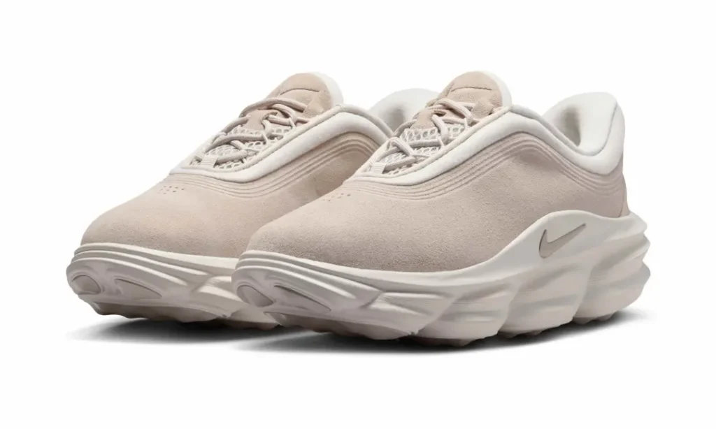 Three-quarter front view of the Nike Motiva Suede featuring a soft beige suede upper, padded collar, mesh tongue, and oversized cushioned mid