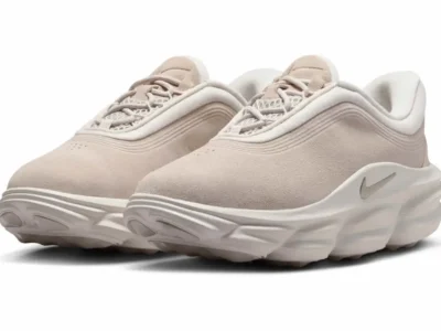 Three-quarter front view of the Nike Motiva Suede featuring a soft beige suede upper, padded collar, mesh tongue, and oversized cushioned mid