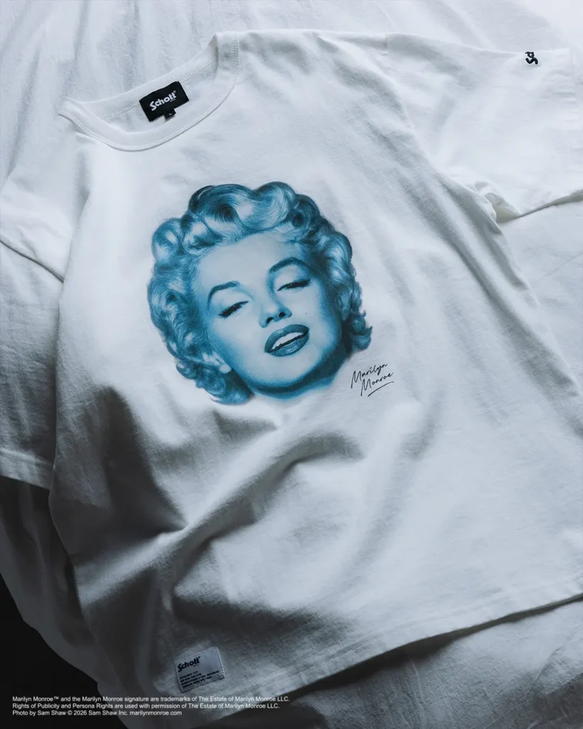 White short-sleeve T-shirt featuring a blue-toned illustrated portrait of Marilyn Monroe across the chest, accented by her signature beneath the artwork