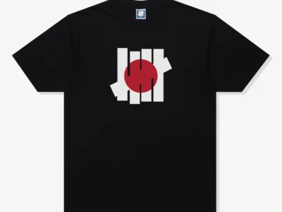 Front view of a black Undefeated 2026 Tee featuring the brand’s five-strike logo reimagined with a red circle inspired by Japan’s flag at the center of the chest
