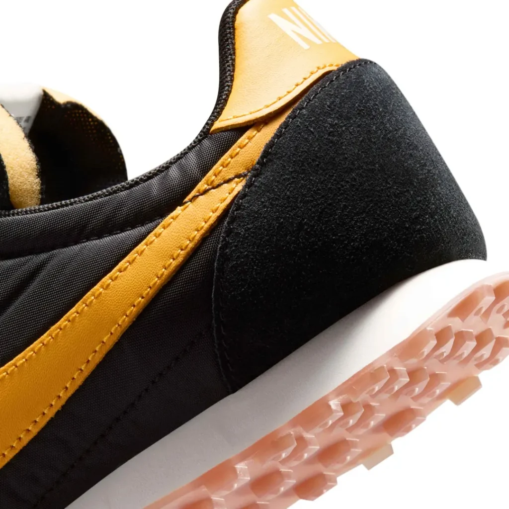 Detailed heel close-up highlighting premium suede textures, yellow leather overlays, white midsole foam, and translucent waffle traction lug