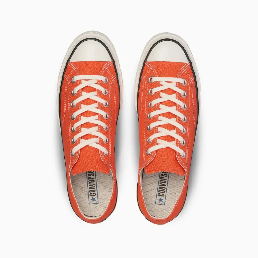 top-down view pair of beige Converse Chuck Taylor All Star low-top shoe photographed on a clean gray background, highlighting neutral tones and timeless style