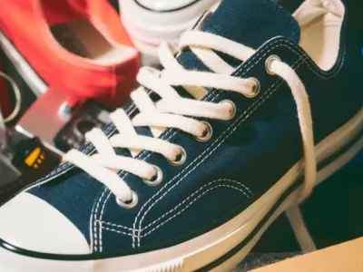 Close-up view of the navy Converse Chuck Taylor All Star low-top shoe highlighting textured canvas construction, contrast white stitching, metal eyelets, and cream lace