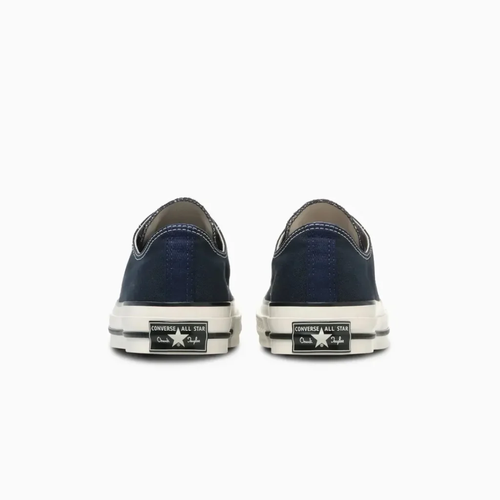 Rear view of the navy Converse Chuck Taylor All Star low-top shoe highlighting the signature heel patch, textured canvas upper, and durable rubber outsole