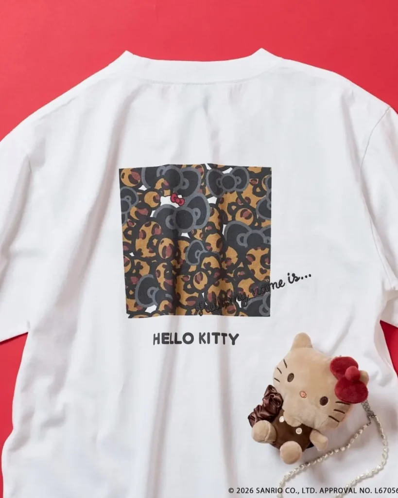 White Hello Kitty graphic T-shirt featuring a small embroidered Hello Kitty motif on the chest and a camouflage-inspired character print across the back panel