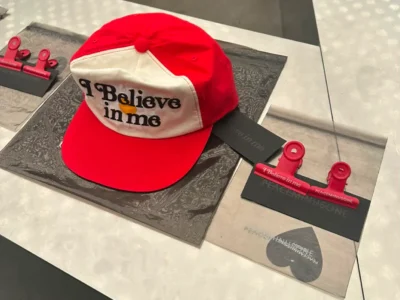 Display of the limited-edition PEACEMINUSONE x VERDY “I Believe in Me” trucker cap and matching red bulldog clips at Lotte World Tower