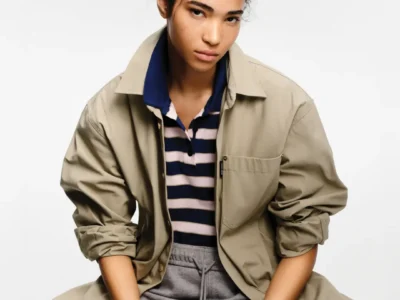 Model styled in a relaxed beige overshirt, striped polo shirt, and grey sweatpants, showcasing Canada Goose’s elevated summer essential